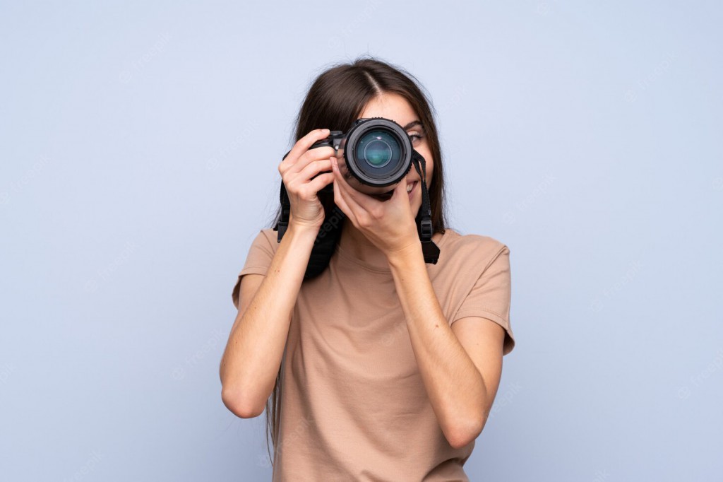 young-woman-over-isolated-blue-wall-with-a-professional-camera_1368-67129